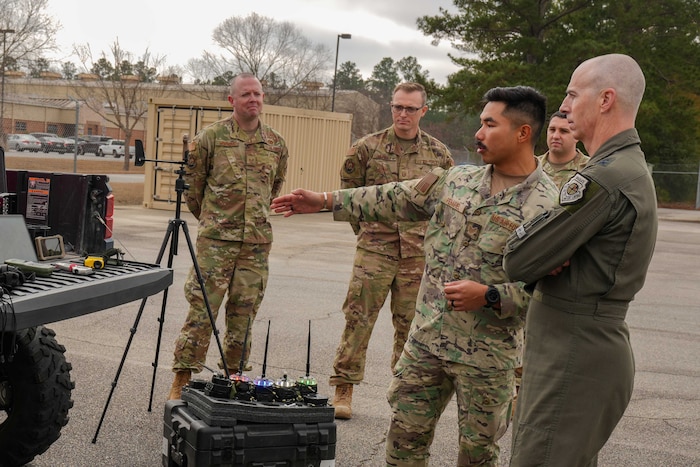 an Airman points at equipment while others look on