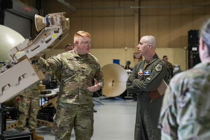 an Airman explains a piece of equipment to a commander