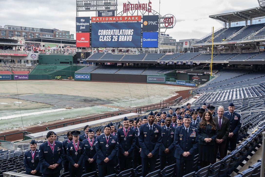 A group poses for a photo in the stands of a baseball stadium.