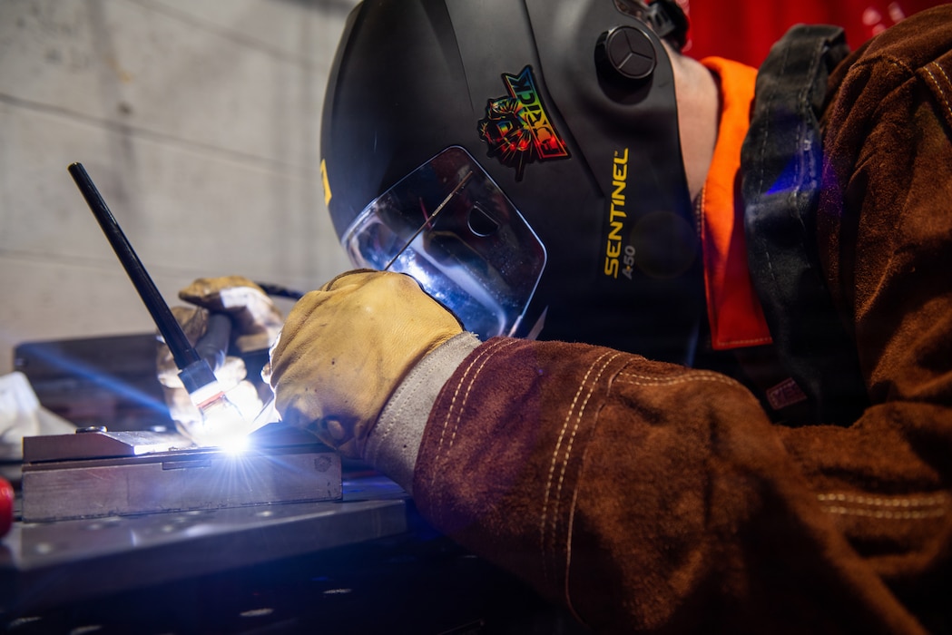 Airman practices welding metal.