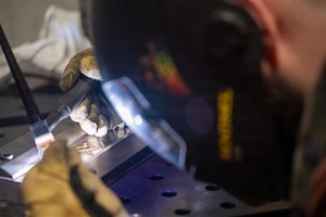 Close up over the shoulder of Airman welding