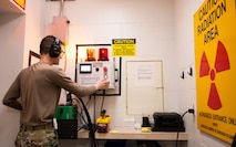 An Airman presses a button to simulate activating an X-ray system.