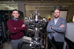Shelby Fields (left), Ph.D., U.S. Naval Research Laboratory (NRL) materials research engineer, and Steven Bennett, Ph.D., NRL materials scientist, pose beside a magnetron sputter system in Washington, D.C., Feb. 2, 2026. Scientists at NRL use this magnetron sputter system to synthesize epitaxial thin films for new materials discovery. (U.S. Navy photo by Sarah Peterson)
