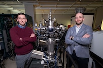 Shelby Fields (left), Ph.D., U.S. Naval Research Laboratory (NRL) materials research engineer, and Steven Bennett, Ph.D., NRL materials scientist, pose beside a magnetron sputter system in Washington, D.C., Feb. 2, 2026. Scientists at NRL use this magnetron sputter system to synthesize epitaxial thin films for new materials discovery. (U.S. Navy photo by Sarah Peterson)