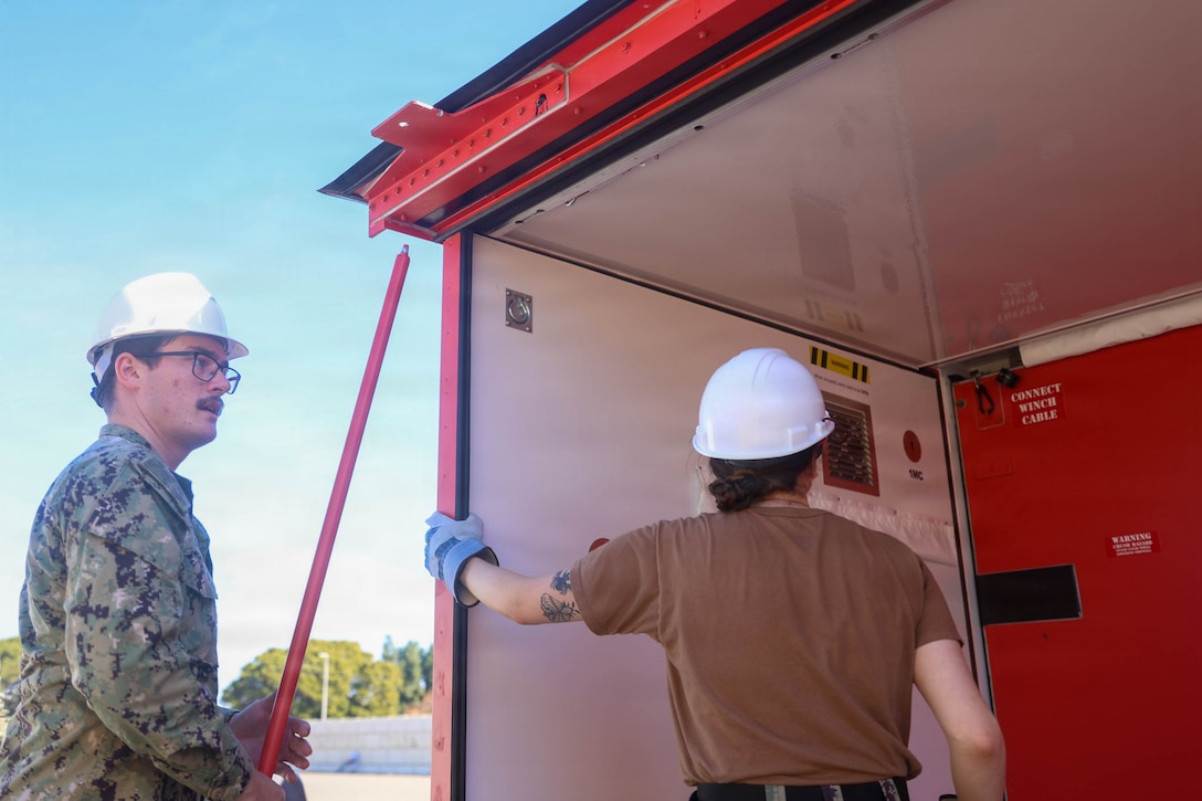 U.S. Navy Hospital Corpsman 3rd Class Nathan Wilson, a general duty nursing services corpsman assigned to the hospital ship USNS Mercy (T-AH 19), left, and Hospital Corpsman 2nd Class Lindsay McCarthney, a general duty nursing services corpsman assigned to the hospital ship USNS Mercy (T-AH 19), expand a Rapid Emplacement Medical (REM) during Exercise Steel Knight at Naval Air Station North Island in Coronado, California, Dec. 2, 2025. The Marine Corps Warfighting Laboratory/Futures Directorate examines future operating environments to generate threat-informed operating concepts and capabilities and, through experimentation, provide analytically supported recommendations to inform future force design and development activities. (U.S. Marine Corps photo by Cpl. Michael Bartman)