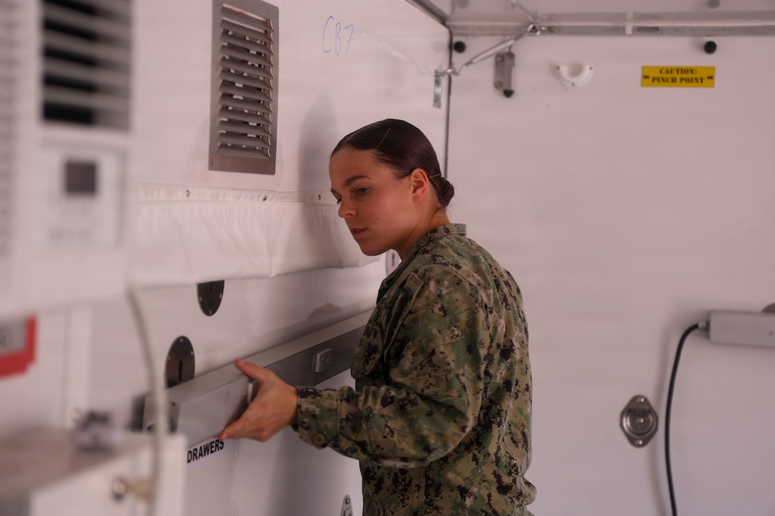 U.S. Navy Hospital Corpsman 3rd Class Julia Cash, assigned to the hospital ship USNS Mercy (T-AH 19), attaches a power strip inside a Rapid Emplacement Medical (REM) during Exercise Steel Knight at Naval Air Station North Island in Coronado, California, Dec. 2, 2025. The Marine Corps Warfighting Laboratory/Futures Directorate examines future operating environments to generate threat-informed operating concepts and capabilities and, through experimentation, provide analytically supported recommendations to inform future force design and development activities. (U.S. Marine Corps photo by Cpl. Michael Bartman)