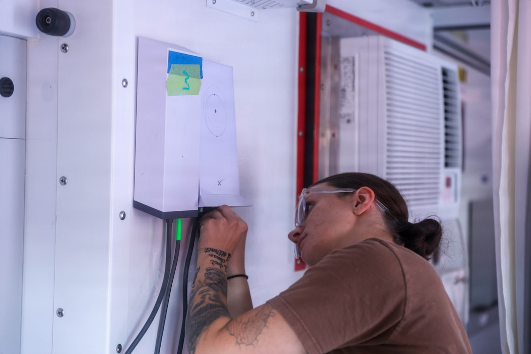 U.S. Navy Hospital Corpsman 2nd Class Ashlyn Gilmore, a general duty nursing services corpsman assigned to the hospital ship USNS Mercy (T-AH 19), establishes connectivity inside a Rapid Emplacement Medical (REM) during Exercise Steel Knight at Naval Air Station North Island in Coronado, California, Dec. 2, 2025. The Marine Corps Warfighting Laboratory/Futures Directorate examines future operating environments to generate threat-informed operating concepts and capabilities and, through experimentation, provide analytically supported recommendations to inform future force design and development activities. (U.S. Marine Corps photo by Cpl. Michael Bartman)