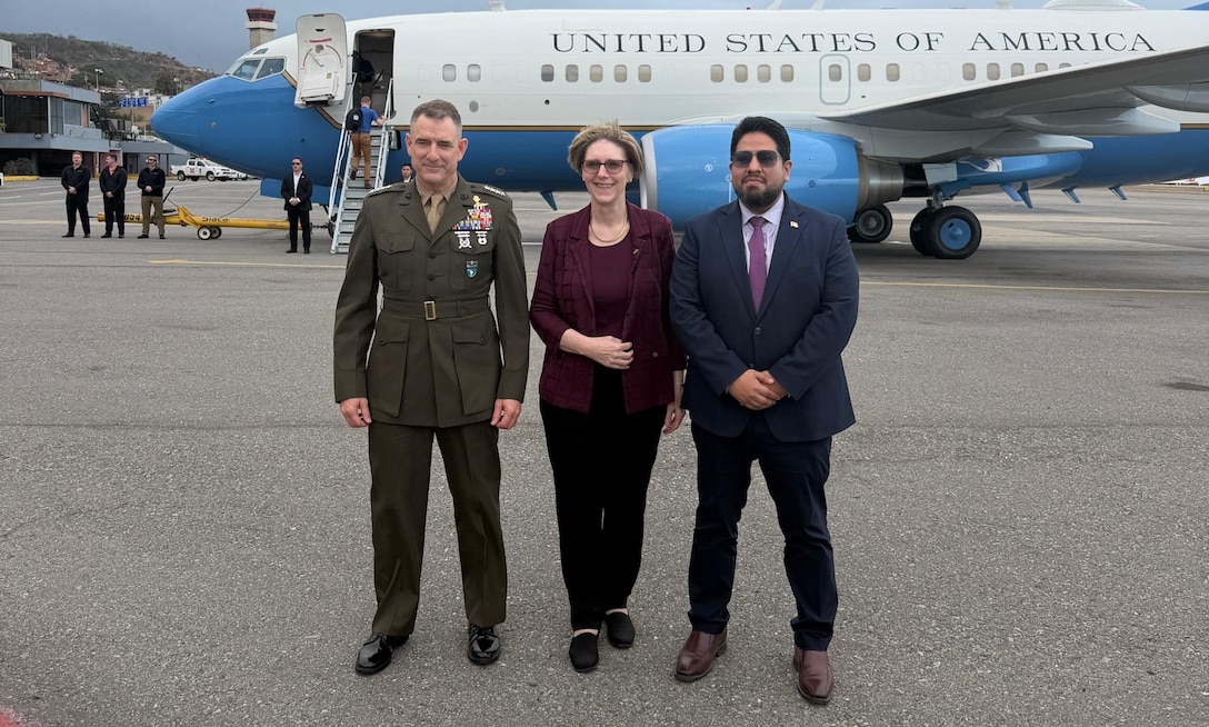 Three people pose for a photo in front of a jet.