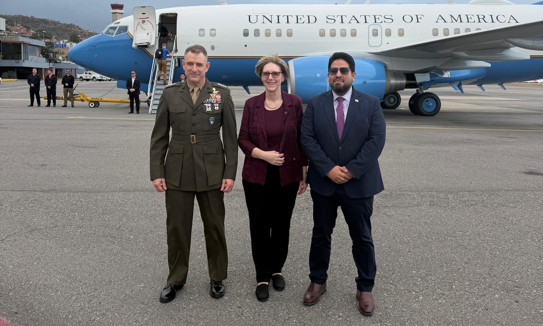 Three people pose for a photo in front of a jet.