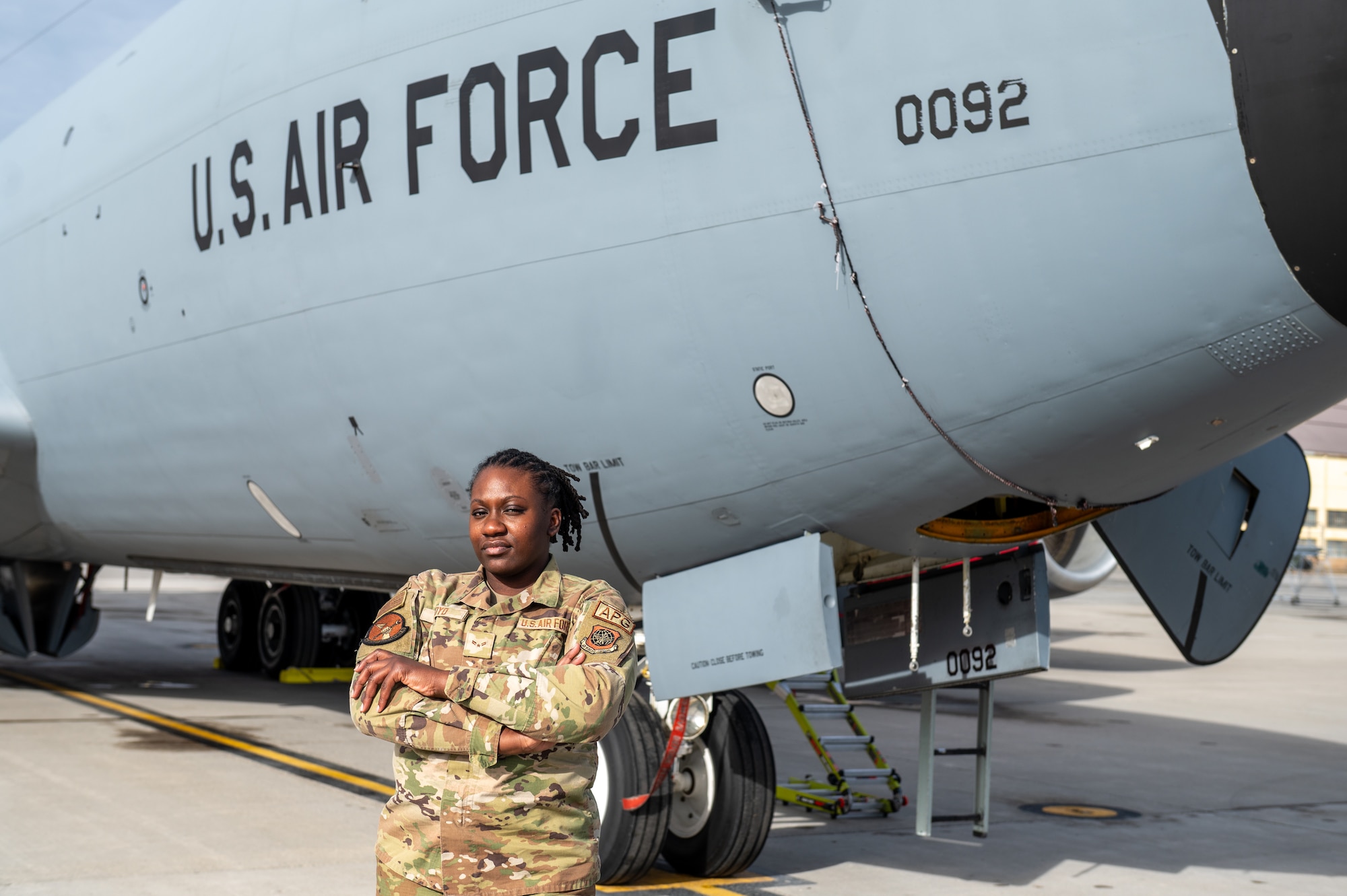 A military member poses for a photo in front of an airplane.