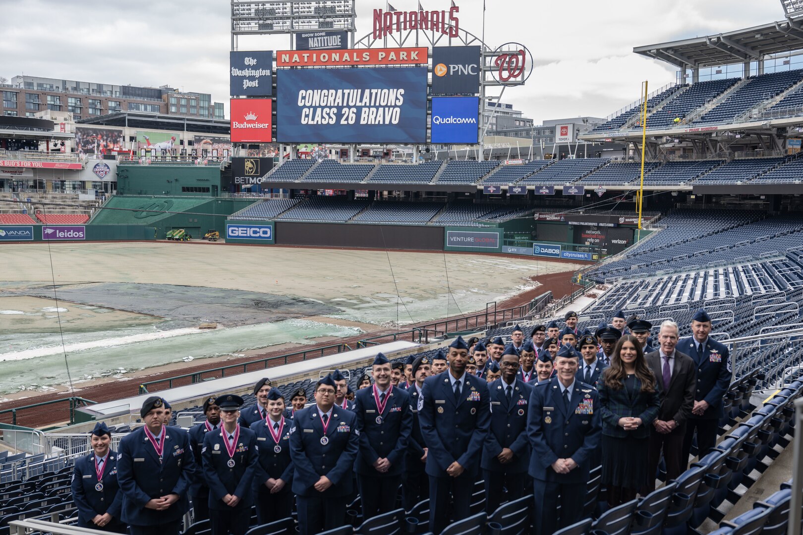A group poses for a photo in the stands of a baseball stadium.