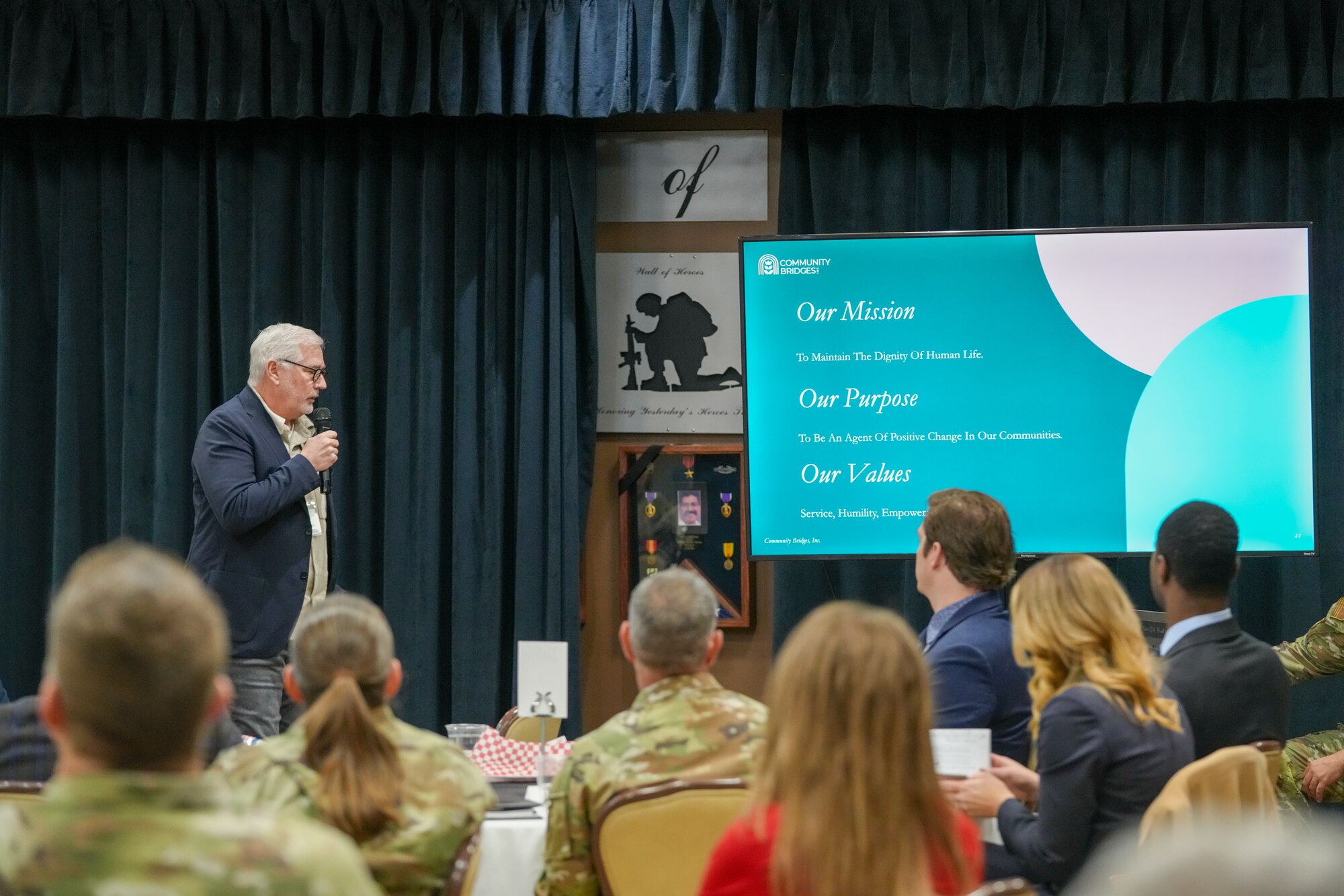 A man stands in front of a screen and briefs Airmen and community members on the progress of the new Horizons Behavioral Health Care during the Base Community Council.
