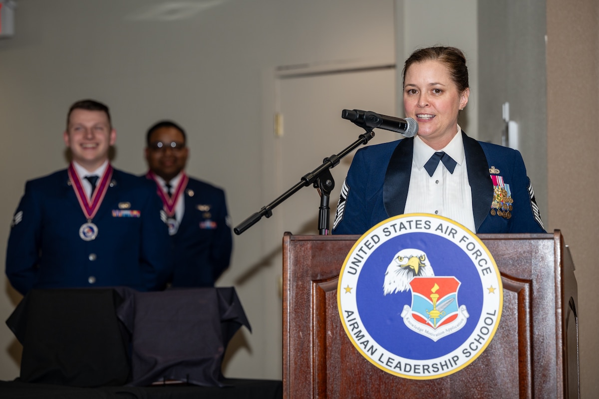 A woman, wearing formal Air Force military dress uniform stand behind podium