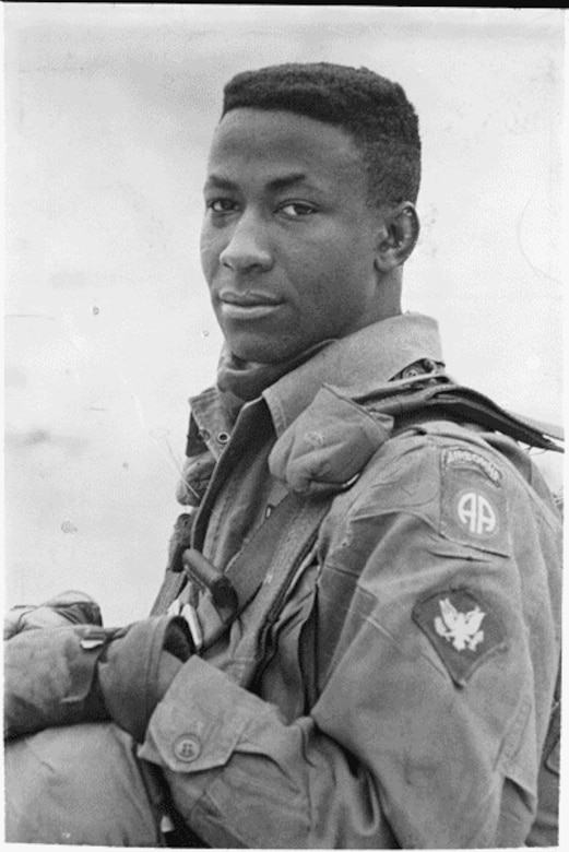 A man wearing a military uniform looks into the distance.