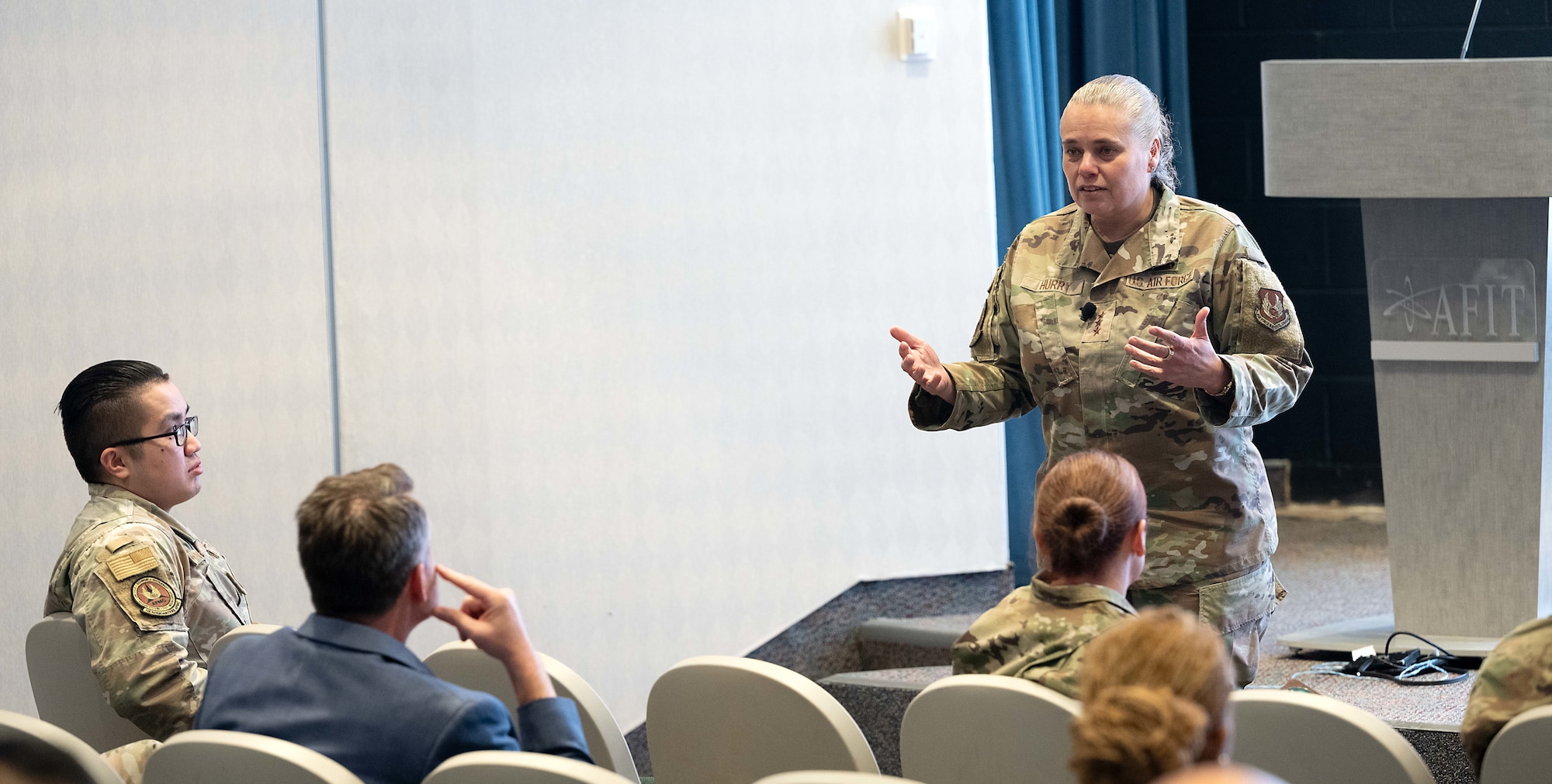 A female Airman speaks to a crowd.