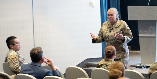 A female Airman speaks to a crowd.