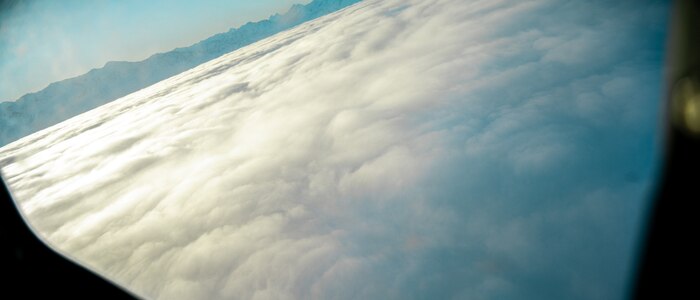 A view from above a layer of clouds through an aircraft window.