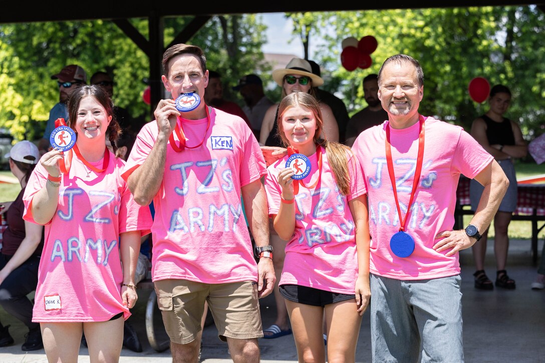 4 people in matching shirts show off their award for winning the summer picnic games.