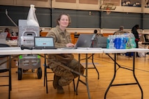 A photo of a woman sitting at the front desk for a blood drive.