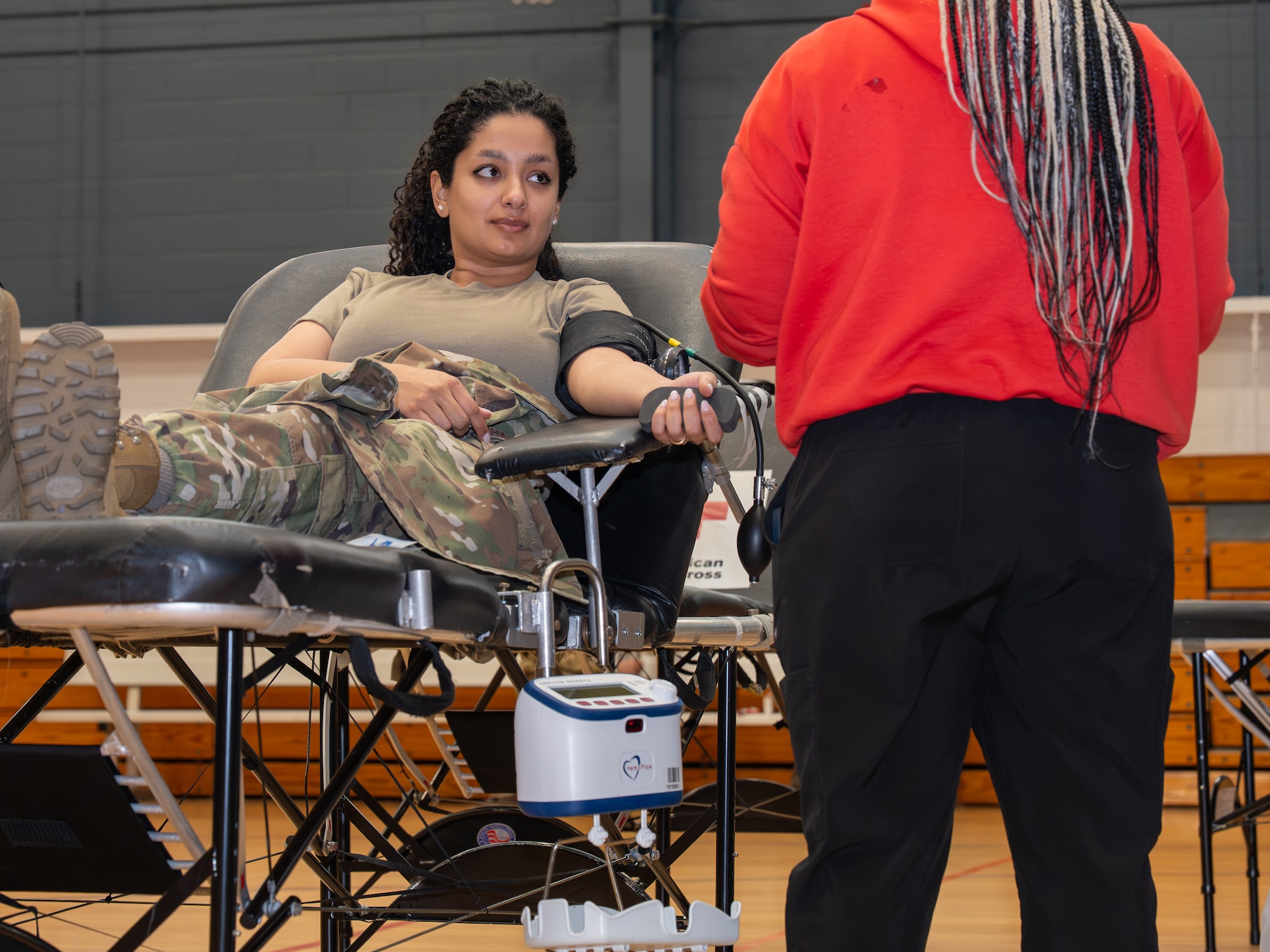 A photo of a woman getting her blood drawn in a gymnasium.