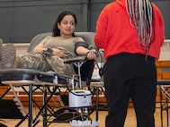 A photo of a woman getting her blood drawn in a gymnasium.
