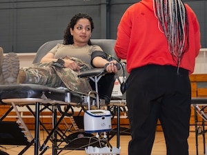 A photo of a woman getting her blood drawn in a gymnasium.