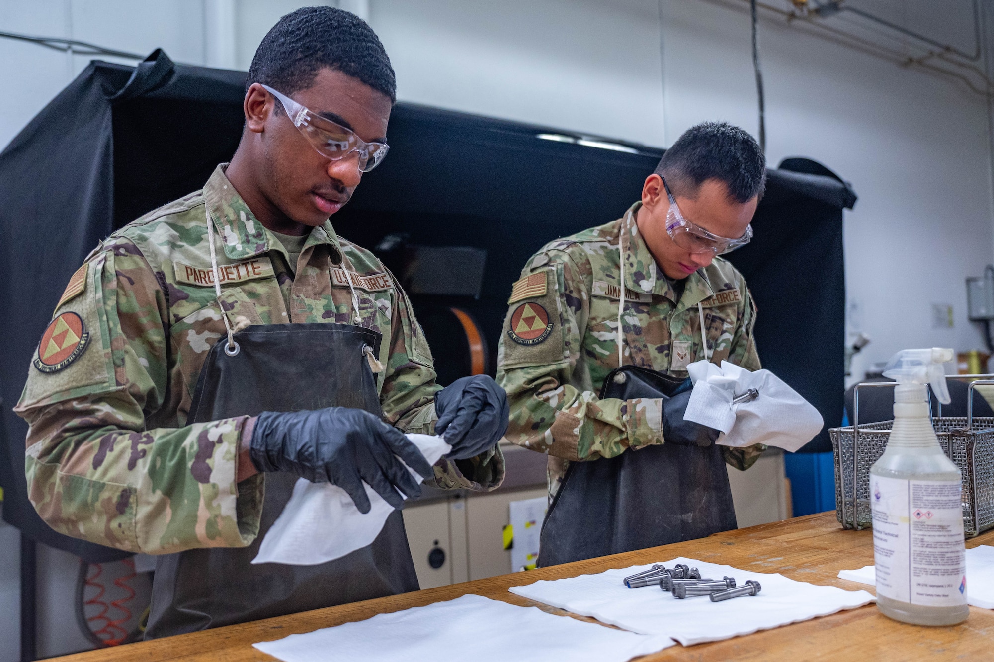 U.S. Air Force Airman Kobe Parquette and Airman 1st Class Dominador Jamanila, both 56th Equipment Maintenance Squadron non-destructive inspection apprentices, clean F-16 Fighting Falcon bolts, Feb. 17, 2026, at Luke Air Force Base, Arizona.