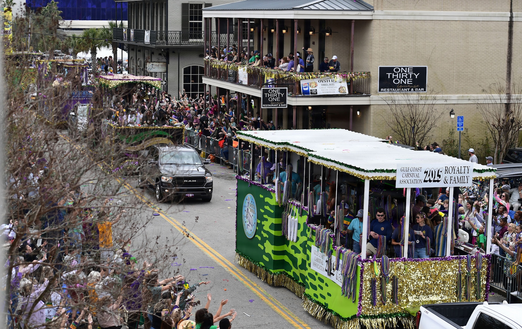 Parad floats move down a street with spectators on both sides.