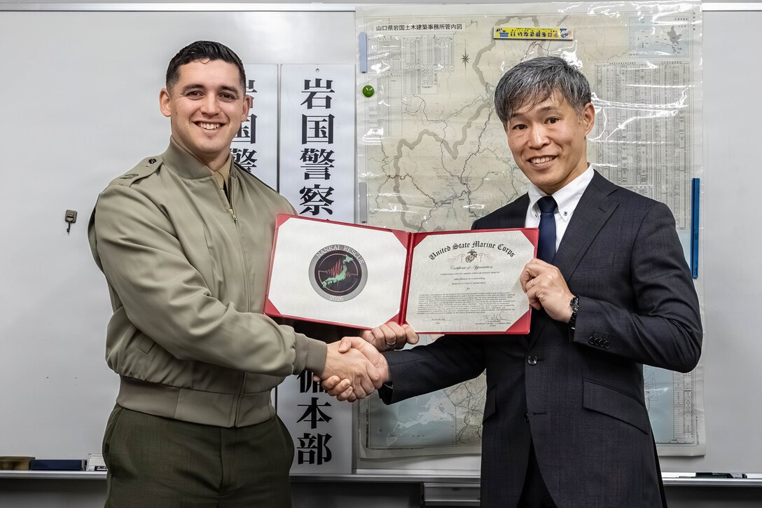 U.S. Marine Corps Capt. John Staton, the deputy provost marshal, with Headquarters and Headquarters Squadron (HHS), Marine Corps Air Station Iwakuni, a native of Illinois, and Shuichi Yoshiyuki, the chief of security section, Iwakuni Police Station, pose for a photo in Iwakuni City, Japan, February 10, 2026. Iwakuni Police Department was presented a certificate of appreciation recognizing their support during exercise Nankai Rescue 2026. (U.S. Marine Corps photo by Lance Cpl. Donald Dugger)