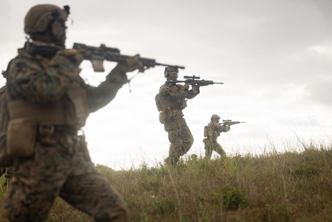 A U.S. Marine with 12th Littoral Combat Team, 12th Marine Littoral Regiment, 3rd Marine Division, communicates with his teammates during a fire team sized attack on Camp Schwab, Okinawa, Japan, Dec. 4, 2025. 12th LCT executed a field training exercise, employing multiple weapons systems and various sized elements to strengthen battlefield capabilities and build team cohesion. (U.S. Marine Corps photo by Lance Cpl. Robert Blanks)