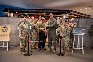 A group of people pose for a photo and cut a ribbon.