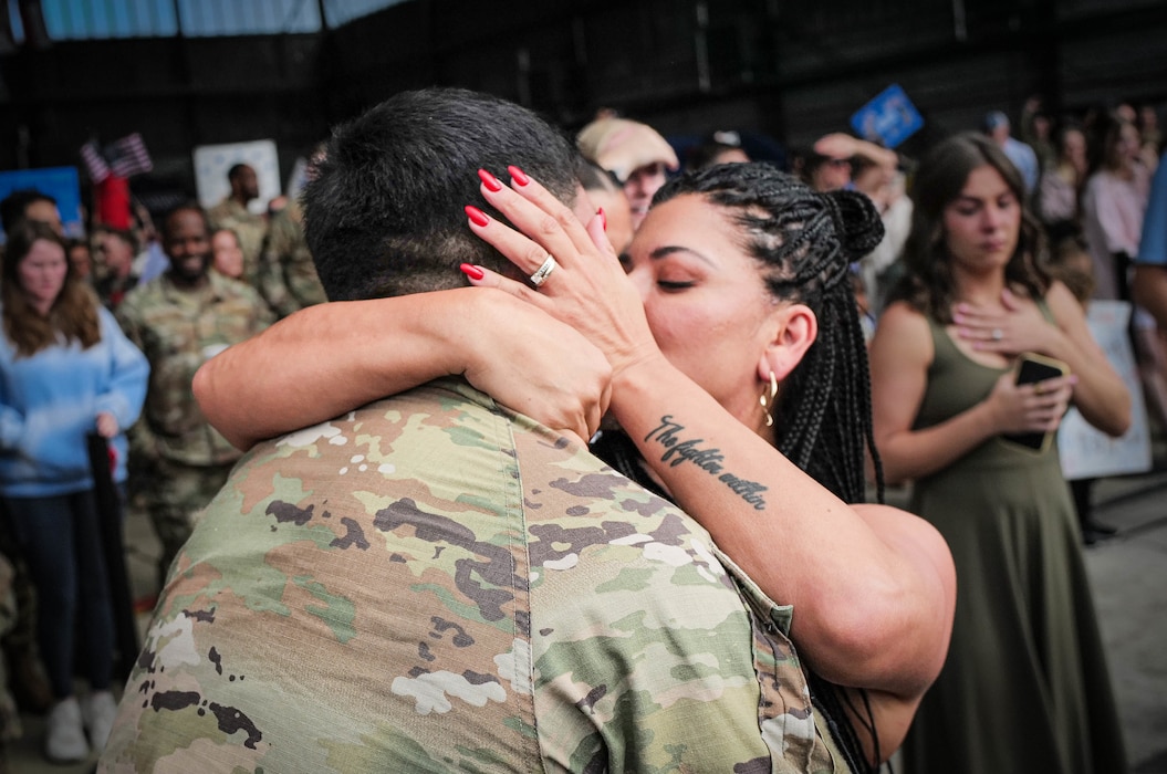 A couple shares their first embrace after months of separation during a redeployment event at Spangdahlem Air Base, Germany, July 23, 2025, as Airmen return from deployment to the U.S. Central Command area of responsibility. The redeploying personnel are assigned to the 480th Fighter Squadron, 480th Fighter Generation Squadron, 52nd Maintenance Group, 52nd Operations Support Squadron, 52nd Logistics Readiness Squadron and 52nd Munitions Maintenance Group. Their return marks the successful completion of a critical combat airpower mission and the reintegration of Saber Airmen with their families.