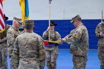 U.S. Army Col. Frank Tantillo, commander of the 86th Infantry Brigade Combat Team (Mountain), Vermont National Guard, and Command Sgt. Maj. Andrew Campagne, command sergeant major of the 86th Infantry Brigade Combat Team (Mountain), unfurl the brigade colors during a Joint Multinational Training Group–Ukraine transfer of authority ceremony at Grafenwoehr Training Area, Germany, Feb. 18, 2026.
