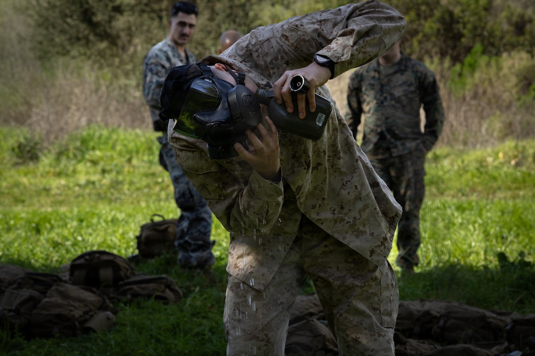 A U.S. Marine with 1st Battalion, 25th Marine Regiment, demonstrates cleansing protocols during an Intermediate Location (ILOC) event held at Camp Pendleton, California, Feb. 9, 2026. ILOC is a pre-deployment event to ensure readiness, emphasizing small-unit leadership roles and responsibilities. (U.S. Marine Corps photo by Lance Cpl. Claire Cheney)