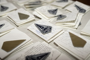 New U.S. Space Force patches sit atop notes from Guardians from around the Space Force in preparation for the U.S. Space Force Basic Military Training graduation patching ceremony at Bob Hope Theater, Joint Base San Antonio-Lackland, Texas, Feb., 17, 2026. The ceremony marks the end of a trainee’s BMT program and is the first of several graduation events symbolizing the transition from trainee to Guardian, connecting them to the service’s core values. (U.S. Air Force photo by Jonathan R. Mallard)