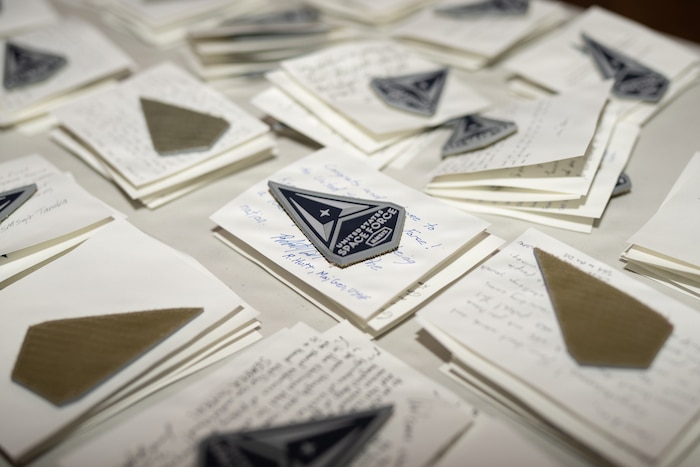 New U.S. Space Force patches sit atop notes from Guardians from around the Space Force in preparation for the U.S. Space Force Basic Military Training graduation patching ceremony at Bob Hope Theater, Joint Base San Antonio-Lackland, Texas, Feb., 17, 2026. The ceremony marks the end of a trainee’s BMT program and is the first of several graduation events symbolizing the transition from trainee to Guardian, connecting them to the service’s core values. (U.S. Air Force photo by Jonathan R. Mallard)