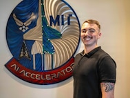 Airman poses for a photo in front of a sign.