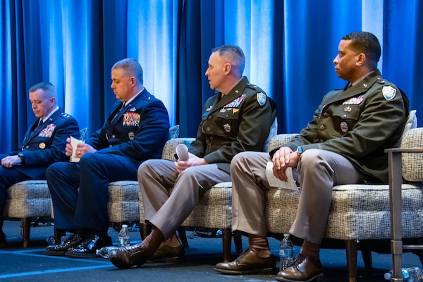 Four military leaders sit on a stage.