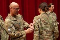 Chief Master Sergeant of the Space Force John Bentivegna places a new U.S. Space Force  patch on the uniform of graduating Space Force Spc. Shayla Town during a Basic Military Training patching ceremony at Bob Hope Theater, Joint Base San Antonio-Lackland, Texas, Feb. 17, 2026. The patching ceremony is the first graduation event and symbolizes the transition from trainee to Guardian, connecting the new Guardians to their service’s core values. CMSSF participated in the event before speaking to the graduates about the importance of their mission to dominate the space domain and secure our nation's future. (U.S. Air Force photo by Jonathan R. Mallard)