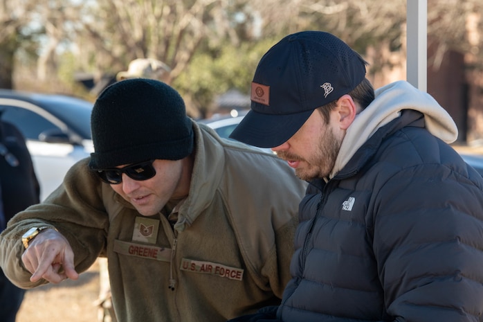 A photo of two men watching a screen and talking.