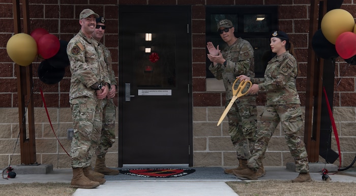 Base leadership and Security Forces Squadron cut ribbon outside of new kennel facility.