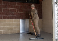 Airman sweeps water out of the kennel.
