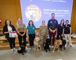Brooke Army Medical Center Facility Dog Program handlers and their dogs accept treats and supplies during the BAMC Auxiliary Welfare Grant Ceremony at BAMC, Joint Base San Antonio, Fort Sam Houston, Texas, Feb. 17, 2026. The welfare committee approved 26 grant requests totaling more than $20,000 to help support patient care at BAMC. (DoW Photo by Garron Webster)