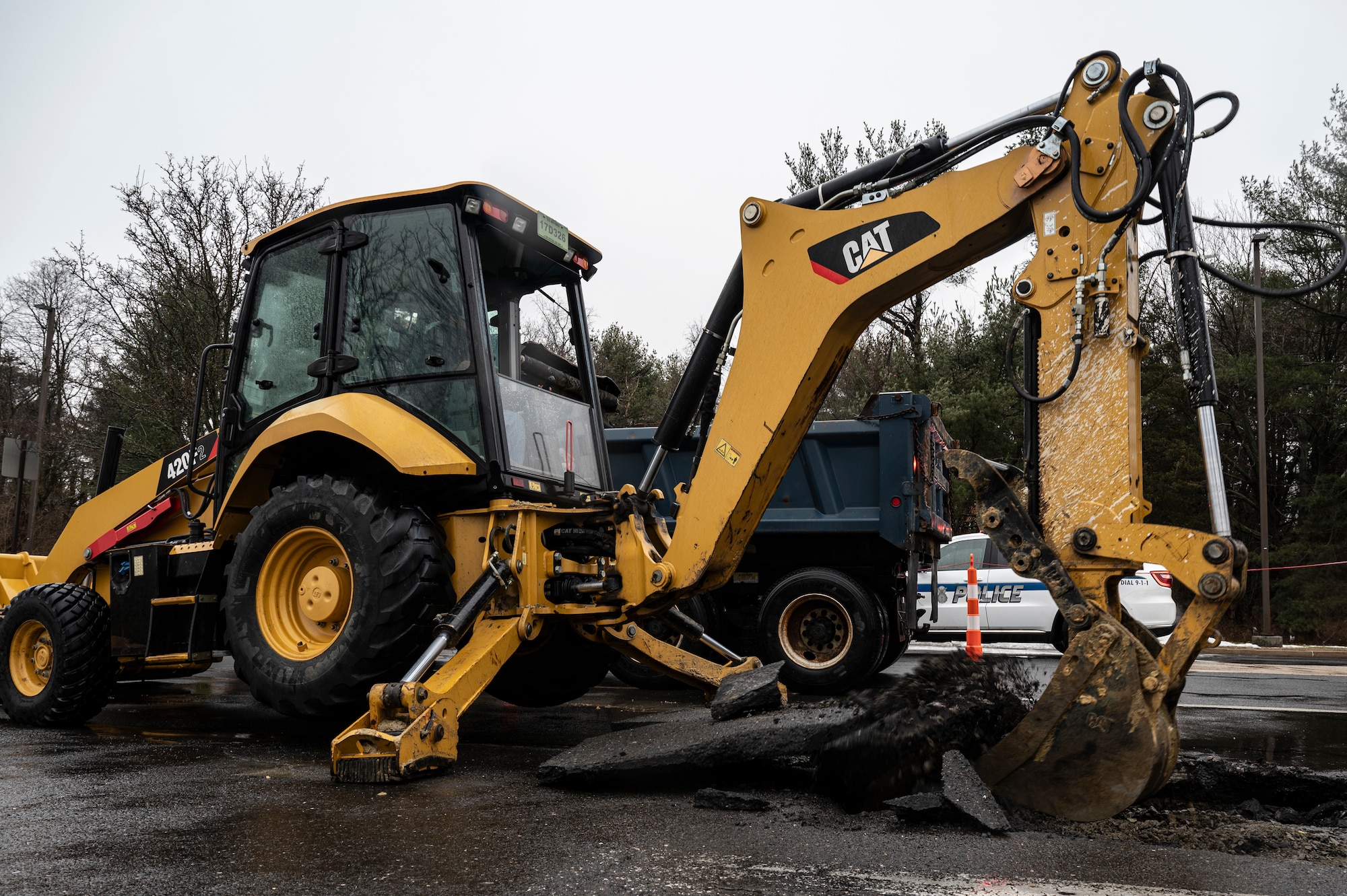 Corey Kourtner, 87th Civil Engineer Squadron civilian heavy equipment and pavement technician, breaks and removes ground with a backhoe during a sinkhole repair at Joint Base McGuire-Dix-Lakehurst, N.J., Feb. 20, 2026. Kourtner removed the ground to further diagnose the severity of the sinkhole and determine necessary repairs. (U.S. Air Force photo by Airman 1st Class Francine D. Martin)