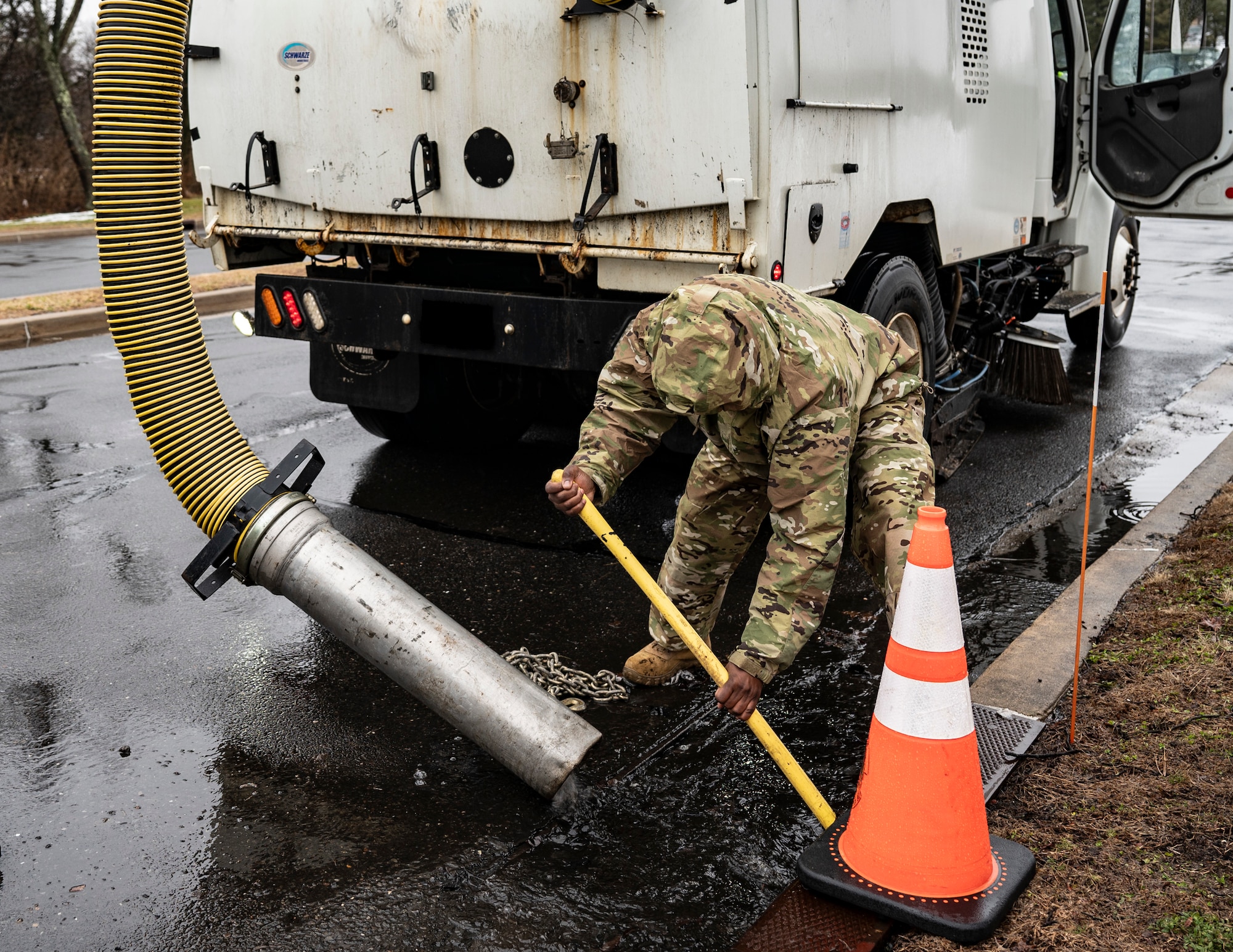 U.S. Air Force Senior Airman Abou Suwareh, 87th Civil Engineer Squadron heavy equipment and pavement journeyman, clears debris and water from a drain during a sinkhole repair at Joint Base McGuire-Dix-Lakehurst, N.J., Feb. 20, 2026. Water was removed before potentially causing further expansion of the sinkhole. (U.S. Air Force photo by Airman 1st Class Francine D. Martin)