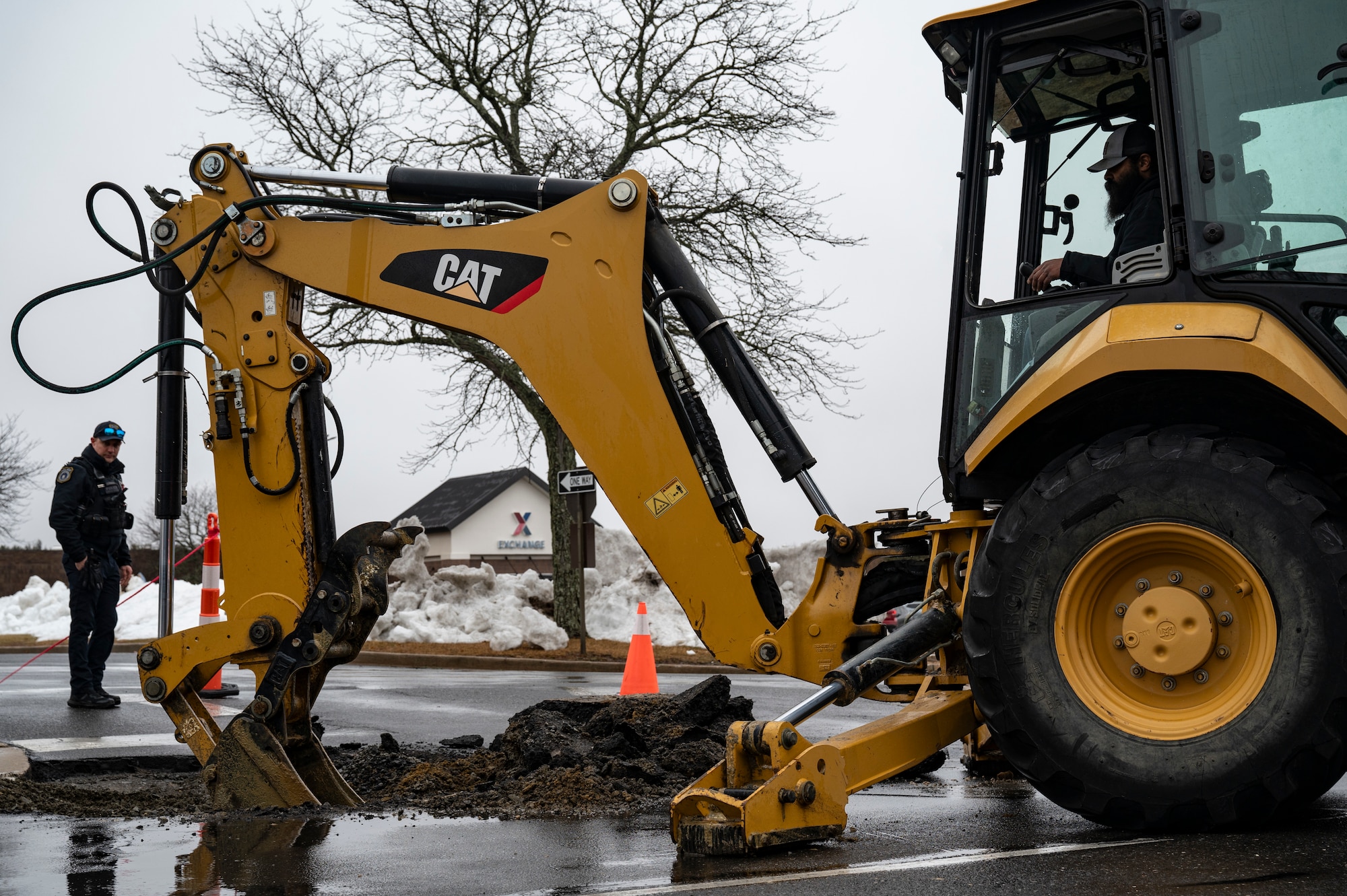 Corey Kourtner, 87th Civil Engineer Squadron civilian heavy equipment and pavement technician, breaks and removes ground with a backhoe during a sinkhole repair at Joint Base McGuire-Dix-Lakehurst, N.J., Feb. 20, 2026. Crews also removed water at the site due to the damage from heavy rainfall. (U.S. Air Force photo by Airman 1st Class Francine D. Martin)
