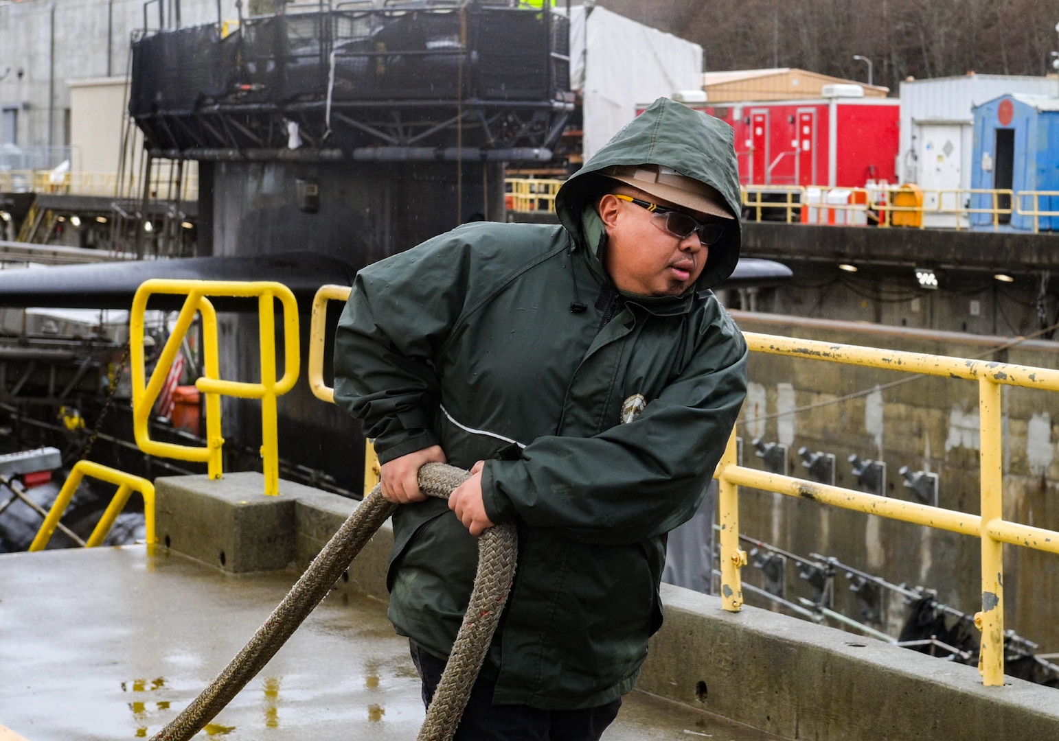 Trident Refit Facility, Bangor (TRFB) rigger carries mooring line on Naval Base Kitsap’s Delta Pier's dry dock, Dec. 28, 2023.