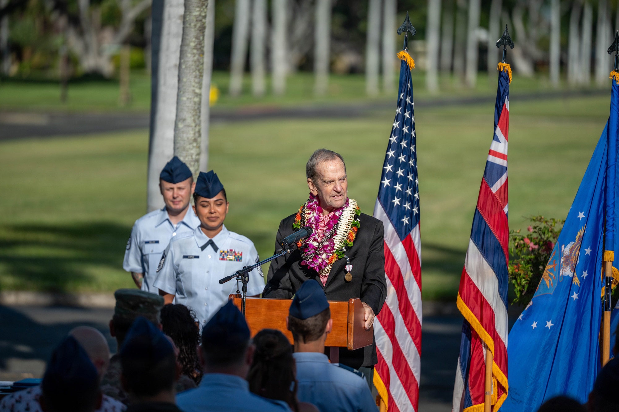 A man who is retiring stands at a podium in front of a crowd, speaks during his retirement ceremony.