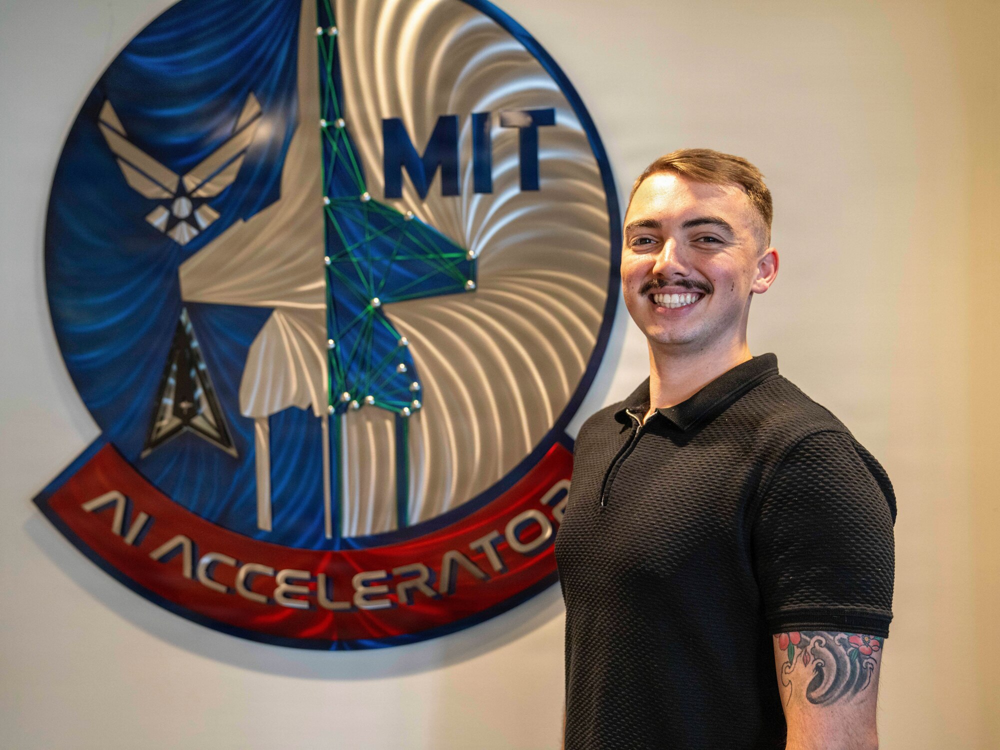 Airman poses for a photo in front of a sign.