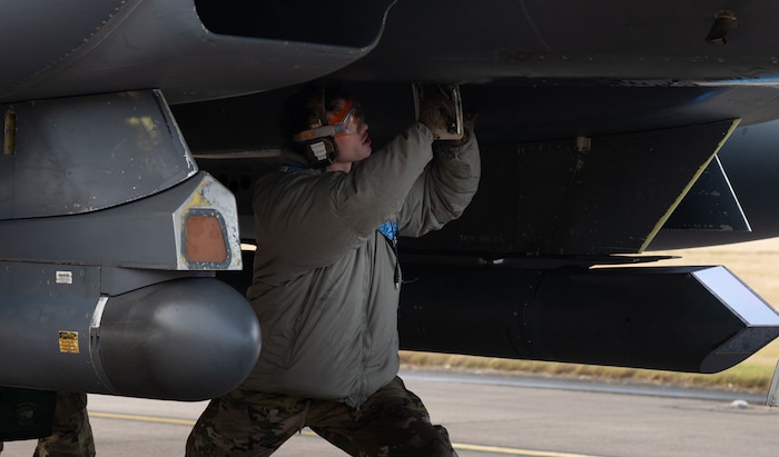 A person crouches under a plane.